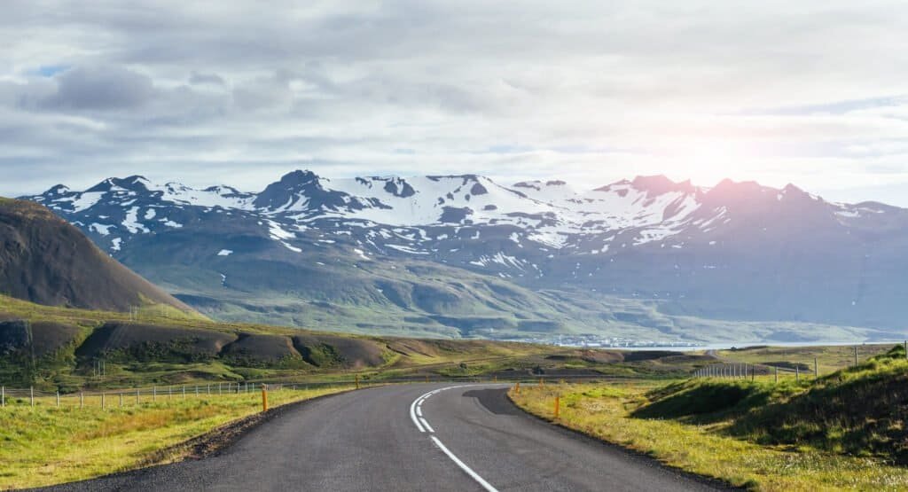 Travel to Iceland. road in a bright sunny mountain landscape. Vatna volcano covered with snow and ice