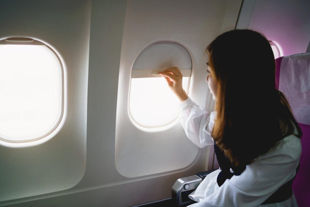 1920 asian woman sitting in a seat in airplane and looking out the window going on a trip asian woman passenger is leaving for a trip by plane on vacation vacation travel concept 1